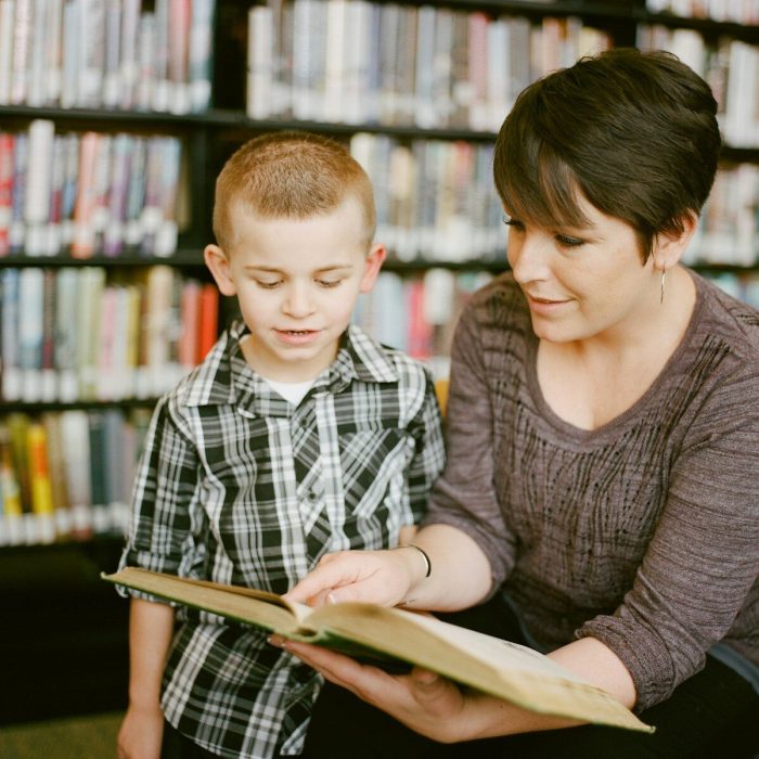 A woman and a child reading a book together in a library